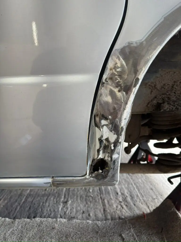 Close up of Mazda Bongo rear arch corrosion before restoration